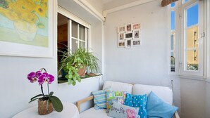Una habitación con un sofá blanco, una mesita con una planta y una pared decorada con cuadros.