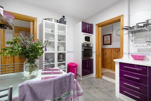 A kitchen with white cabinets, a microwave, and a pink trash bin.