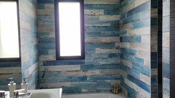 A bathroom with a wooden plank wall design, a window, a bathtub, and a sink with modern fixtures.