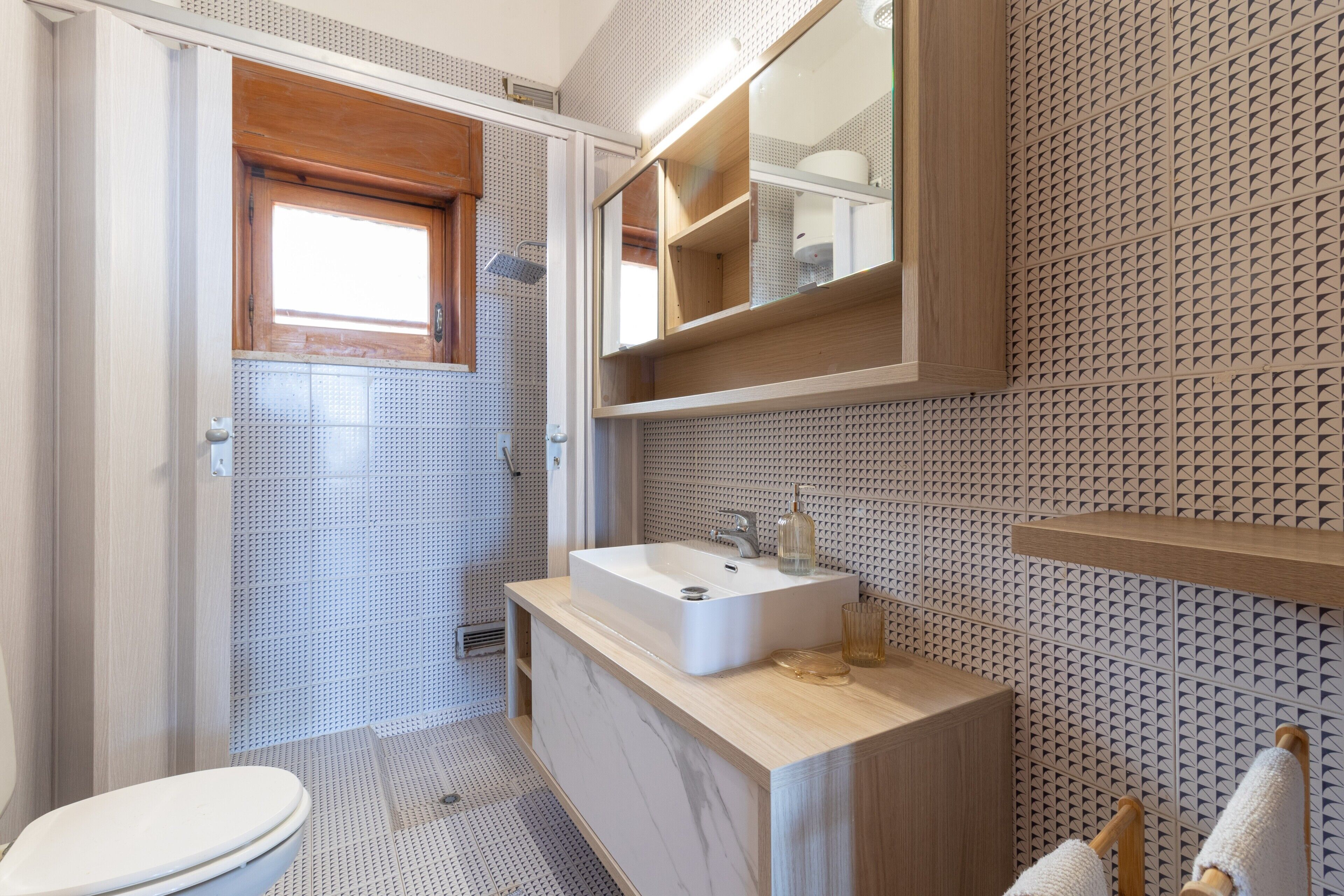 Un bany amb un lavabo blanc, un tocador de fusta, un mirall i una paret amb dibuixos.