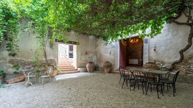 Eine Terrasse im Freien mit Kiesboden, rustikaler Möbel und großen Pflanzgefäßen.