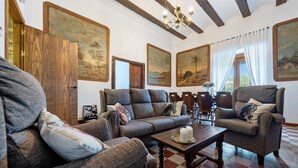 Ein Wohnzimmer mit einer Couch, Sesseln, einem Couchtisch und Bildern an der Wand.