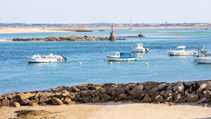 A coastal marina with boats docked, a lighthouse, and a sandy beach. - Holiday Home 'Petite Maison' with Private Terrace and Wi-Fi (Le Croisic)
