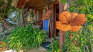A wooden structure with a porch, surrounded by lush greenery and plants. - Chalet 'With Garden and Sea View 100m' with Sea View, Private Terrace and Garden (Plougastel-Daoulas)
