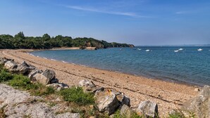 A pebble beach with clear water, a rocky shoreline, and distant hills. - Chalet 'With Garden and Sea View 100m' with Sea View, Private Terrace and Garden (Plougastel-Daoulas)