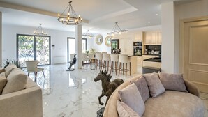 Amplia sala de estar con un sofá grande, una mesa de comedor con sillas, una zona de cocina y una estatua decorativa de un caballo.