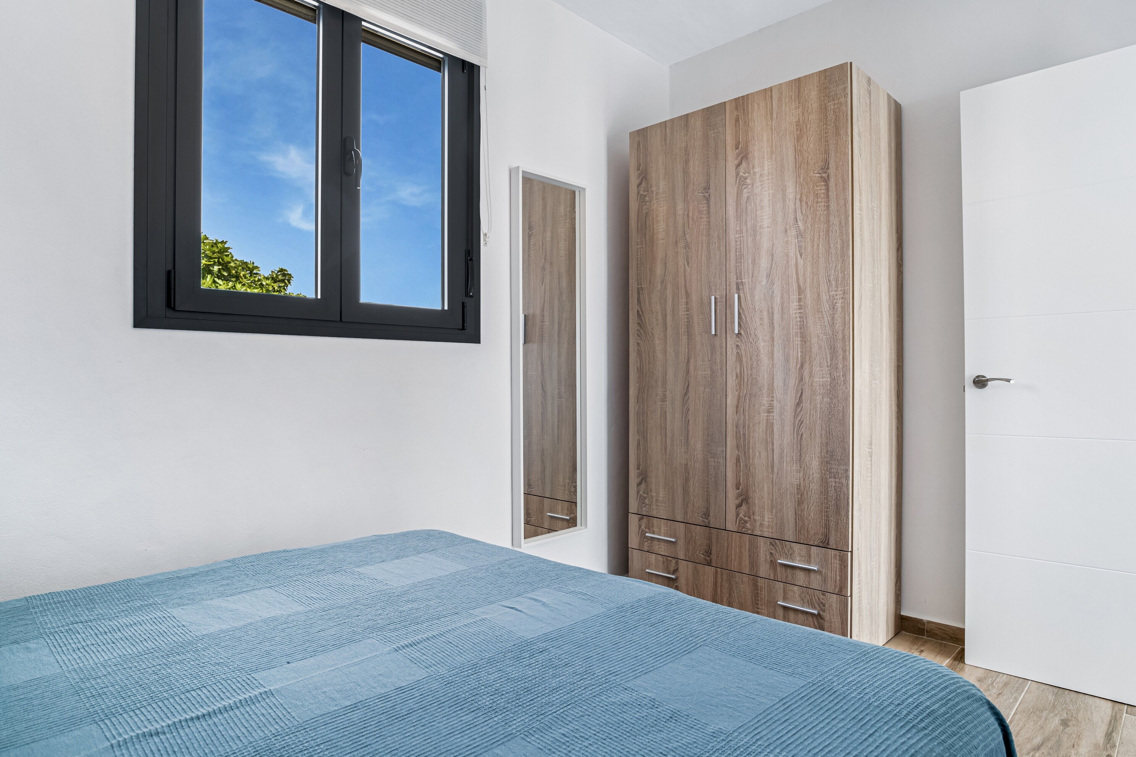 Ein Schlafzimmer mit einem Bett, einem Kleiderschrank, einem Fenster und einer Tür.