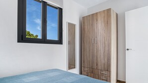 Een slaapkamer met een bed, een kast, een raam en een deur.