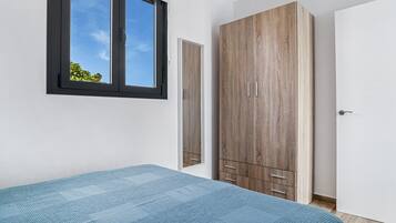 Ein Schlafzimmer mit einem Bett, einem Kleiderschrank, einem Fenster und einer Tür.