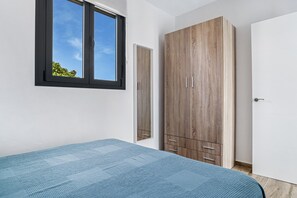 Une chambre à coucher avec un lit, une armoire, une fenêtre et une porte.