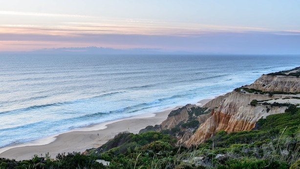 A coastal landscape with a beach, cliffs, and ocean.