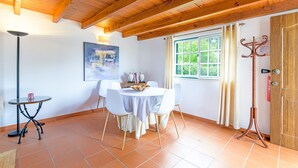A dining area with a round table, white chairs, a floor lamp, and a window with curtains.