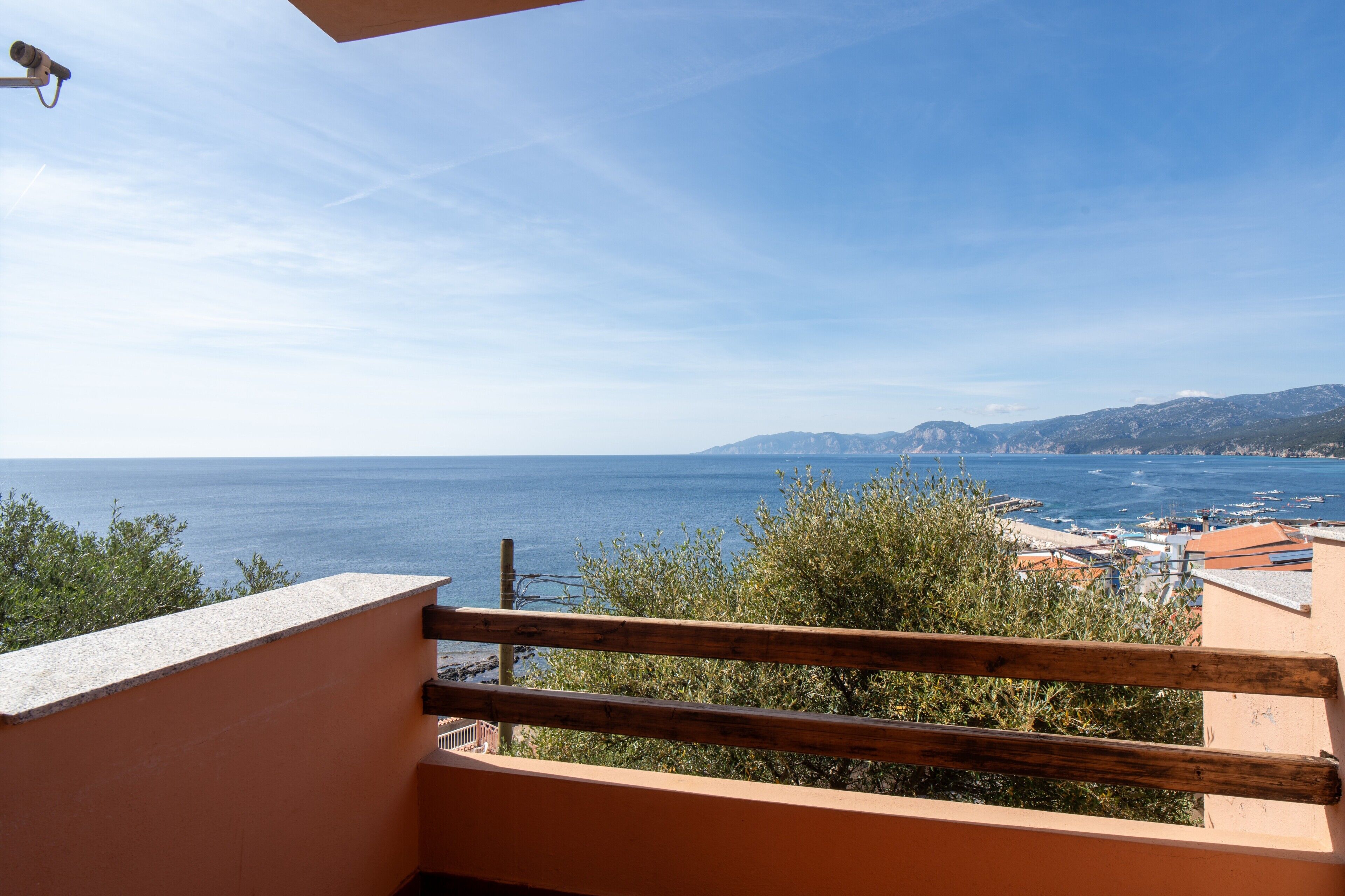 Un balcón con vista al mar y montañas a lo lejos.