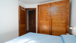 Un dormitorio con cama, armario de madera y mesita de noche con lámpara.