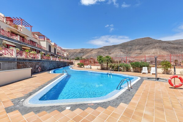 A swimming pool with a red fence, a lifebuoy, and a mountain in the background.