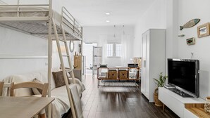 A bunk bed, a TV, a dining table, and a kitchen area with a cabinet. - Studio Apartment 'La Casita Blanca' with Wi-Fi and Air Conditioning (Barbate)