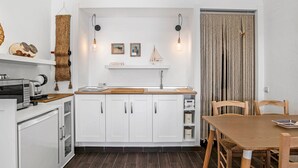 A modern kitchen with white cabinets, a wooden countertop, and a dining area with a wooden table and chairs. - Studio Apartment 'La Casita Blanca' with Wi-Fi and Air Conditioning (Barbate)