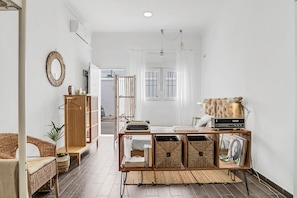 A modern living room with a wicker sofa, a wooden cabinet, and a small table with books and decorative items.