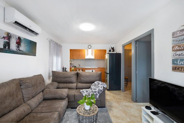 A living room with a sofa, a TV, and a small table with a plant.