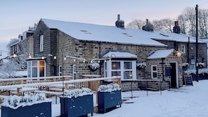 A stone building with a snow-covered roof and a wooden deck. - The Hermit Inn Hideout (Burley Woodhead, near Ilkley)