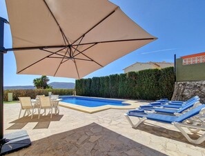 A swimming pool with lounge chairs and an umbrella.
