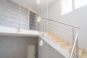 A modern staircase with a glass railing and a pendant light.