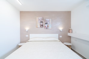 A modern bedroom with a large bed, two bedside tables, a wall-mounted shelf, and two wall-mounted light fixtures.