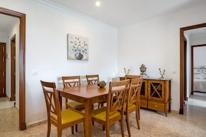 A dining area with a wooden table and chairs, a painting on the wall, and a cabinet with decorative items.