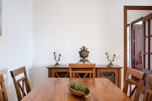 A dining table with chairs, a decorative bowl, and a clock on the wall.