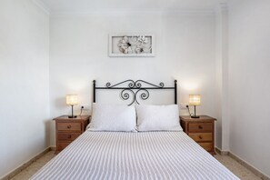 A neatly made bed with a patterned bedspread, two bedside tables with lamps, and a framed artwork on the wall.