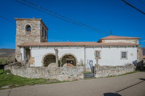 A stone building with a bell tower, arched doorways, and a small gate.