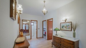 A hallway with wooden flooring, a wooden dresser, a mirror, and a chandelier. - Country House 'El Corcal' with Mountain View, Private Terrace and Wi-Fi (Triollo)