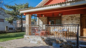 A stone building with a red facade, a balcony with metal railings, and outdoor furniture. - Country House 'El Corcal' with Mountain View, Private Terrace and Wi-Fi (Triollo)