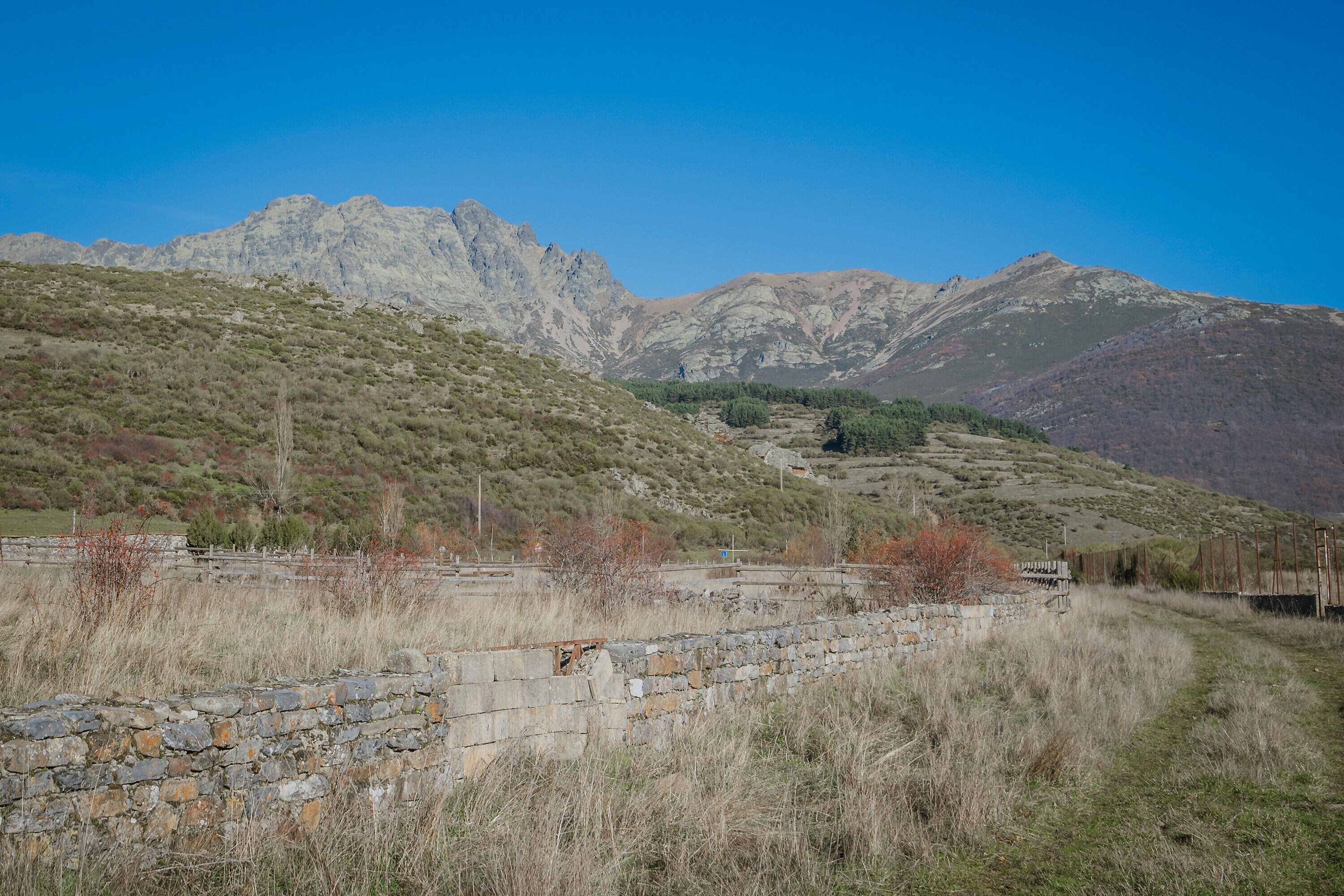 Un paysage montagneux avec un mur de pierre et un sentier.