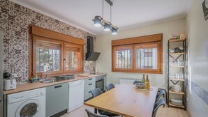A compact kitchen with a wooden table, built-in appliances, and a window with a view. - Country House 'El Corcal' with Mountain View, Private Terrace and Wi-Fi (Triollo)