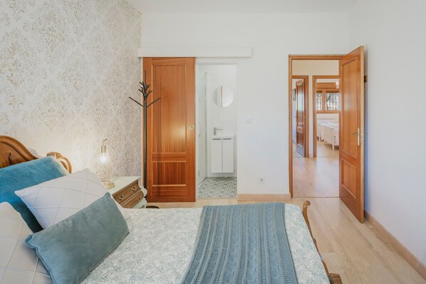 A bedroom with a bed, bedside table, lamp, and wardrobe.