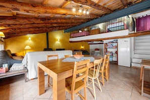 Un interior rústico con una mesa de comedor de madera, sillas, un sofá y un balcón con barandilla.