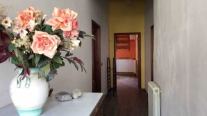 Un corridoio con un vaso di fiori su un tavolo, un termosifone e una porta che dà su un'altra stanza.