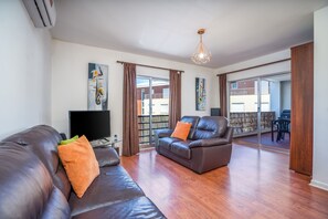Un salon avec un canapé, un téléviseur et un balcon offrant une vue agréable.