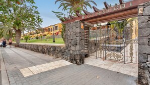 A gated entrance with a stone wall and a wooden sign that reads 'RATLIANTICO.'