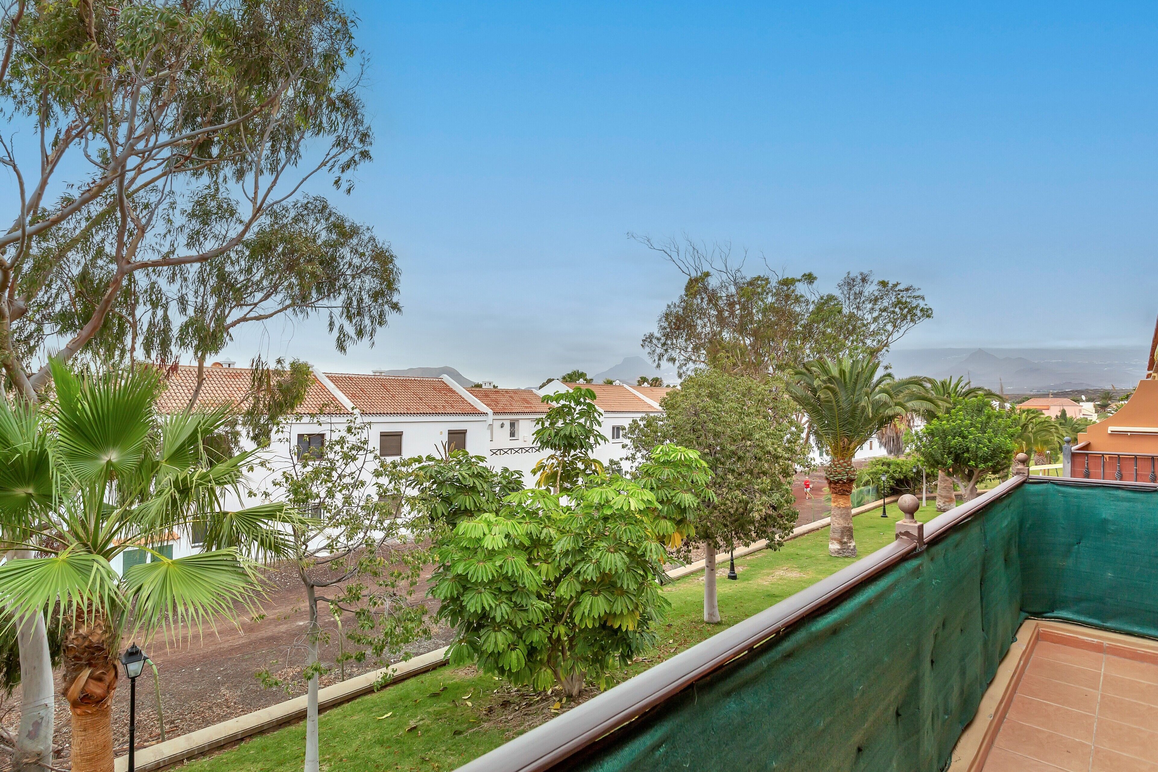 Un balcon donnant sur un quartier résidentiel, avec vue sur des maisons et une voie ferrée.