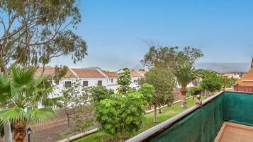 Un balcon donnant sur un quartier résidentiel, avec vue sur des maisons et une voie ferrée.