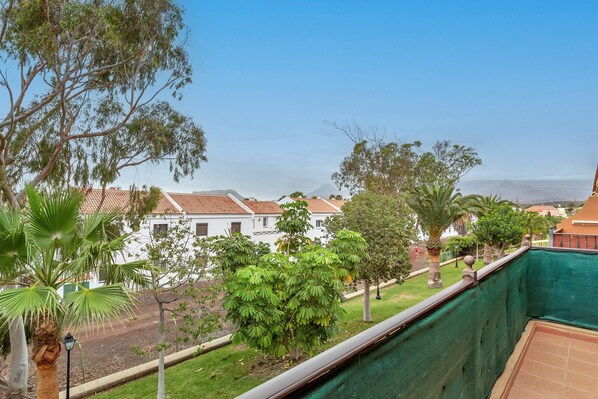 Un balcón con vista a una zona residencial, que incluye casas y una vía de tren.