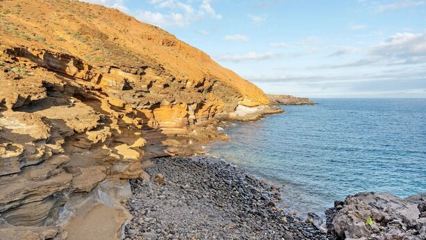 A coastal landscape with rocky cliffs and a clear blue sea.