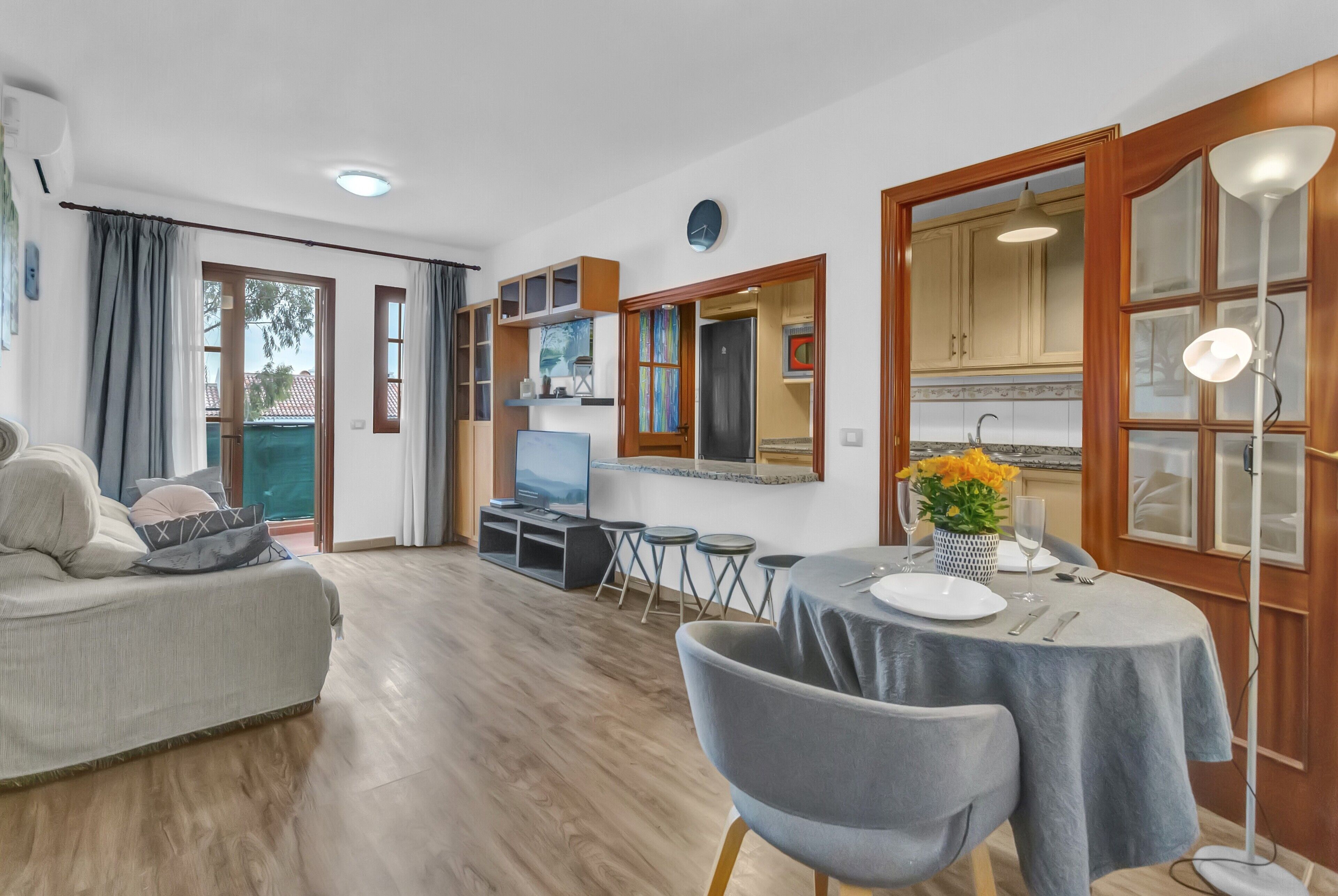 Een moderne woonkamer met een bank, een eettafel met stoelen, een keuken met kasten en een televisie.