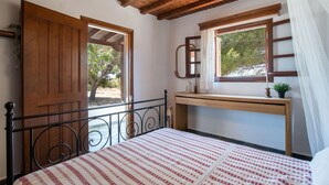 A bedroom with a bed, wooden ceiling, a desk, and a window with a view of trees. - Black Sand Holiday Home with Sea View and Private Terrace (Naxos)