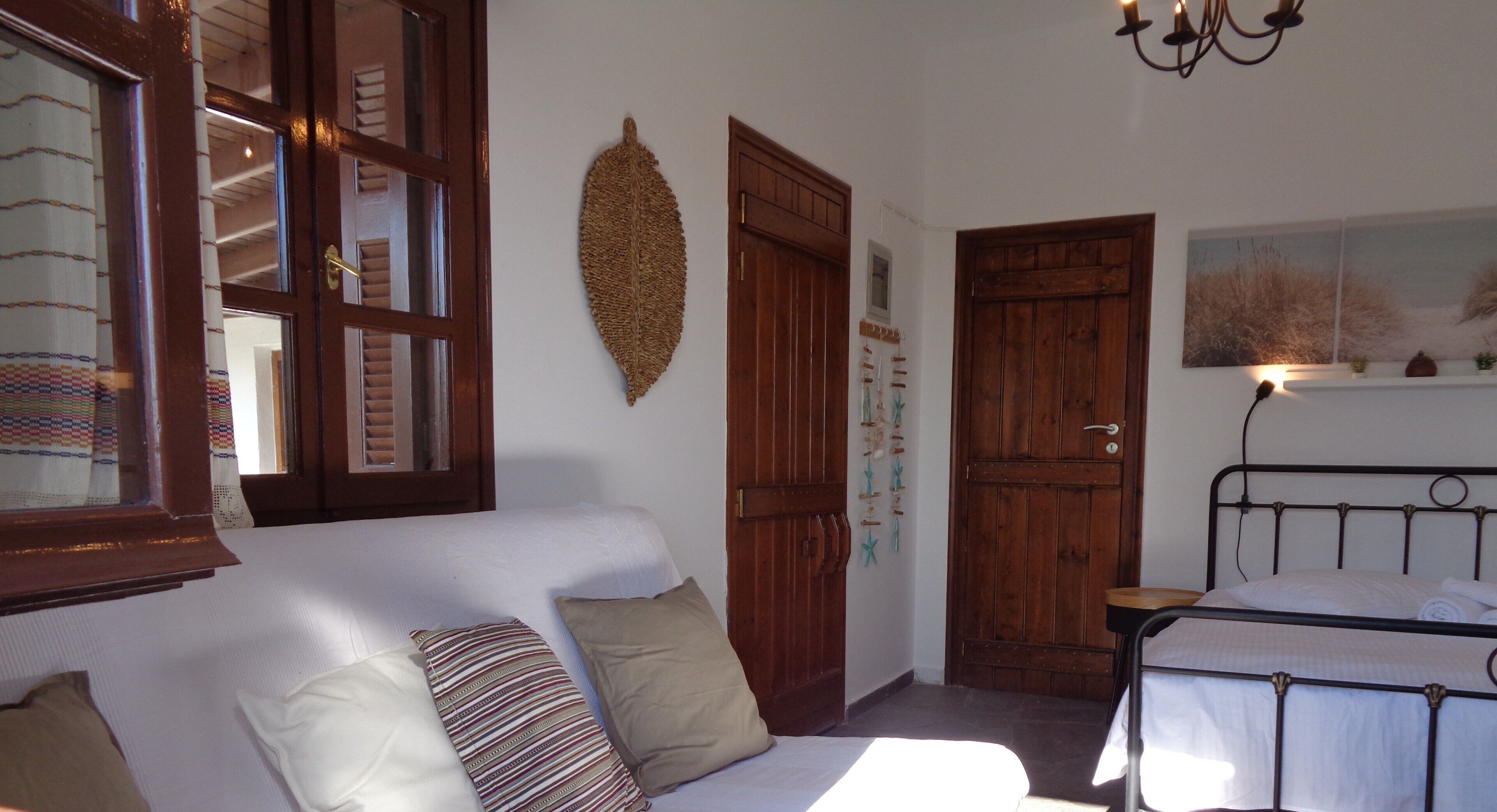 A room with a bed, a wooden door, a white wall, and a window.