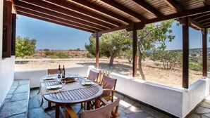 An outdoor dining area with a pergola, a table set for two, and a view of the landscape. - Black Sand Holiday Home with Sea View and Private Terrace (Naxos)