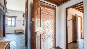 A hallway with a wooden door, a bench, and a stone floor. - Black Sand Holiday Home with Sea View and Private Terrace (Naxos)