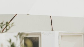Ein weißer Sitzbereich im Freien mit Tisch und Stühlen, einer Weinflasche und einer Tür mit Fenster.